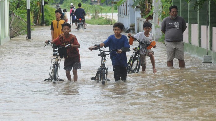 Sejumlah warga melintas di jalan perkampungan yang terendam banjir di Planggu, Trucuk, Klaten, Jawa Tengah, Rabu (15/2/2023). Intensitas hijan deras menyebabkan aliran sungai Dengkeng meluap dan membanjiri pemukiman warga disekitarnya. ANTARA FOTO/Aloysius Jarot Nugroho/hp.