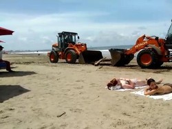 Bule-bule tampak asyik berjemur tanpa menghiraukan adanya alat berat yang sedang bekerja membersihkan sampah di Pantai Seminyak.