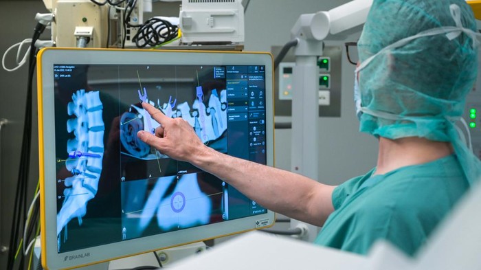 15 February 2023, Saxony-Anhalt, Halle (Saale): Senior physician Bernhard Ullrich (l) and Christoph Wilhelm in the operating room with the new robot. Bergmannstrost Hospital in Halle is putting a new robotic surgical operating system into operation. It also features a 3D imaging robot and a digital navigation system. Photo: Heiko Rebsch/dpa (Photo by Heiko Rebsch/picture alliance via Getty Images)