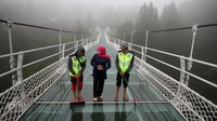 Gubernur Jawa Timur Khofifah Indar Parawansa (kanan) berjalan di atas jembatan gantung kaca di Seruni Point Kawasan Strategis Pariwisata Nasional (KSPN) Bromo-Tengger-Semeru, Probolinggo, Jawa Timur, Rabu (15/2/2023).   