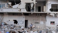 Orang-orang berdiri di rumah mereka yang runtuh akibat gempa mematikan di Jableh, Suriah, 15 Februari 2023. Korban tewas gempa Turki dan Suriah telah menembus 41.000 jiwa per Rabu (15/2). REUTERS/Amr Alfiky  