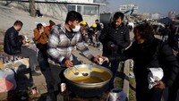 Seorang pria menyajikan makanan kepada orang-orang setelah gempa mematikan di Kahramanmaras, Turki 12 Februari 2023. REUTERS/Suhaib Salem