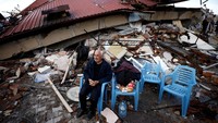 Seorang pria duduk di tengah reruntuhan setelah gempa bumi di Hatay, Turki 7 Februari 2023. REUTERS/Guglielmo Mangiapane  
