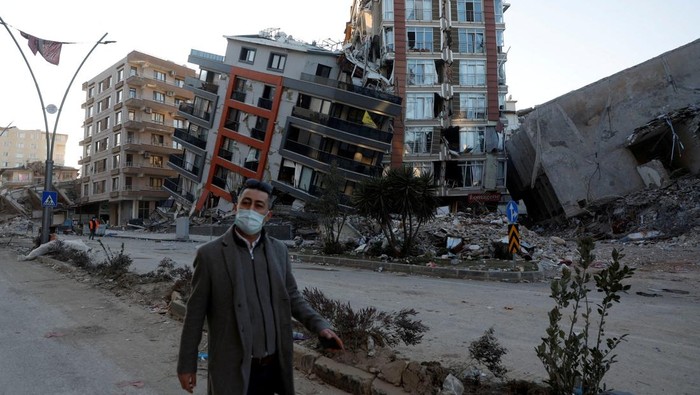 A man walks in front of semi collapsed buildings in the aftermath of a deadly earthquake in Hatay, Turkey February 15, 2023. REUTERS/Clodagh Kilcoyne       TPX IMAGES OF THE DAY
