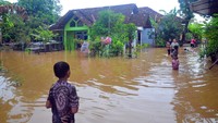 Warga melintasi jalan yang tergenang banjir di Desa, Mejobo, Mejobo, Kudus, Jawa Tengah, Kamis (16/2/2023).  