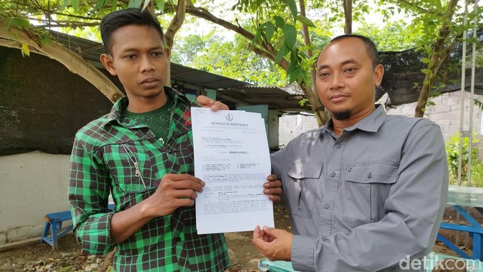 Yogi (kiri) bersama pamannya yang juga penasihat hukumnya menunjukkan laporan polisi.