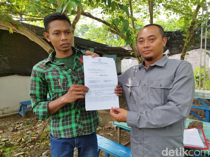 Yogi (kiri) bersama pamannya yang juga penasihat hukumnya menunjukkan laporan polisi.