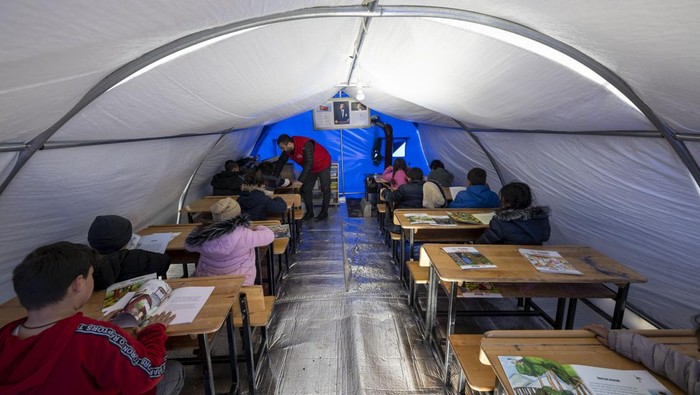 ADIYAMAN, TURKIYE - FEBRUARY 16: Earthquake victim children are seen at a makeshift tent class after voluntary teachers established came together and set up three tents at the Sumerevler Athletic Track, where the tent city is located, in Adiyaman, Turkiye on February 16, 2023. The voluntary teachers, who divided the tents into primary, secondary and high school groups, started their education by hanging the Turkish flags on their doors. On Feb. 06, a strong 7.7 earthquake, centered in the Pazarcik district, jolted Kahramanmaras and strongly shook several provinces, including Gaziantep, Sanliurfa, Diyarbakir, Adana, Adiyaman, Malatya, Osmaniye, Hatay, and Kilis. Later, at 13.24 p.m. (1024GMT), a 7.6 magnitude quake centered in Kahramanmaras' Elbistan district struck the region. (Photo by Aytac Unal/Anadolu Agency via Getty Images)