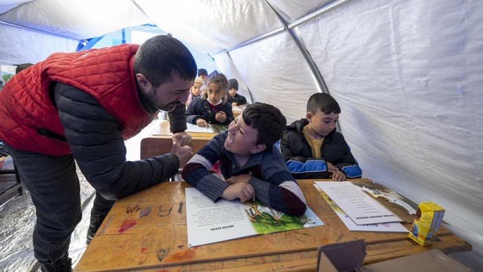 Anak-anak Korban Gempa Turki Lanjutkan Sekolah di Tenda Darurat ADIYAMAN, TURKIYE - FEBRUARY 16: Earthquake victim children are seen at a makeshift tent class after voluntary teachers established came together and set up three tents at the Sumerevler Athletic Track, where the tent city is located, in Adiyaman, Turkiye on February 16, 2023. The voluntary teachers, who divided the tents into primary, secondary and high school groups, started their education by hanging the Turkish flags on their doors. On Feb. 06, a strong 7.7 earthquake, centered in the Pazarcik district, jolted Kahramanmaras and strongly shook several provinces, including Gaziantep, Sanliurfa, Diyarbakir, Adana, Adiyaman, Malatya, Osmaniye, Hatay, and Kilis. Later, at 13.24 p.m. (1024GMT), a 7.6 magnitude quake centered in Kahramanmaras' Elbistan district struck the region. (Photo by Aytac Unal/Anadolu Agency via Getty Images)