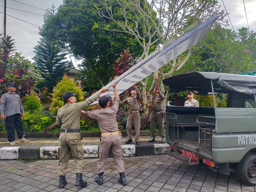 Anggota Satpol PP Badung saat membongkar baliho berisi tuntutan 