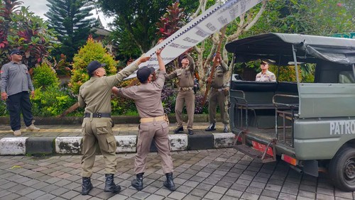 Anggota Satpol PP Badung saat membongkar baliho berisi tuntutan Bendesa Adat Mengwi mundur di simpang Bencingah Mengwi, Badung, Bali, Jumat (17/2/2023).