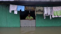 Seorang warga berada di depan rumahnya yang terendam banjir.