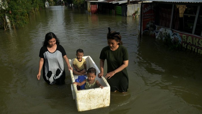 Warga melintasi jalan yang tergenang banjir sambil membawa anaknya di Kecamatan Biringkanaya, Makassar, Sulawesi Selatan, Jumat (17/2/2023). Hujan deras yang mengguyur Kota Makassar sejak Senin  (13/2) malam tersebut merendam permukiman warga hingga ketinggian air mencapai 1 meter di beberapa lokasi sehingga sejumlah kepala keluarga terpaksa mengungsi sementara ke tempat yang lebih aman. ANTARA FOTO/Abriawan Abhe/foc.