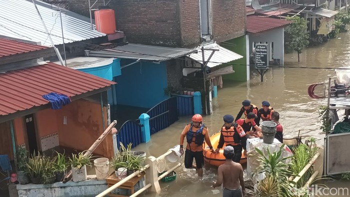 Petugas dan relawan melakukan evakuasi warga menggunakan perahu karet, Jumat (17/2/2023).