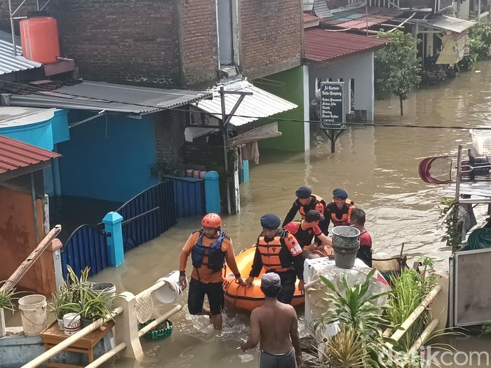 Petugas dan relawan melakukan evakuasi warga menggunakan perahu karet, Jumat (17/2/2023).
