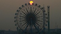 Matahari terbenam saat orang-orang menikmati wahana di sebuah taman hiburan di Basra, Irak. (AP Photo/Nabil al-Jurani)  