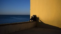 Seorang wanita membaca di tepi laut saat sinar matahari pertama menyinari kota Cadiz, Spanyol. (AP Photo/Emilio Morenatti)  