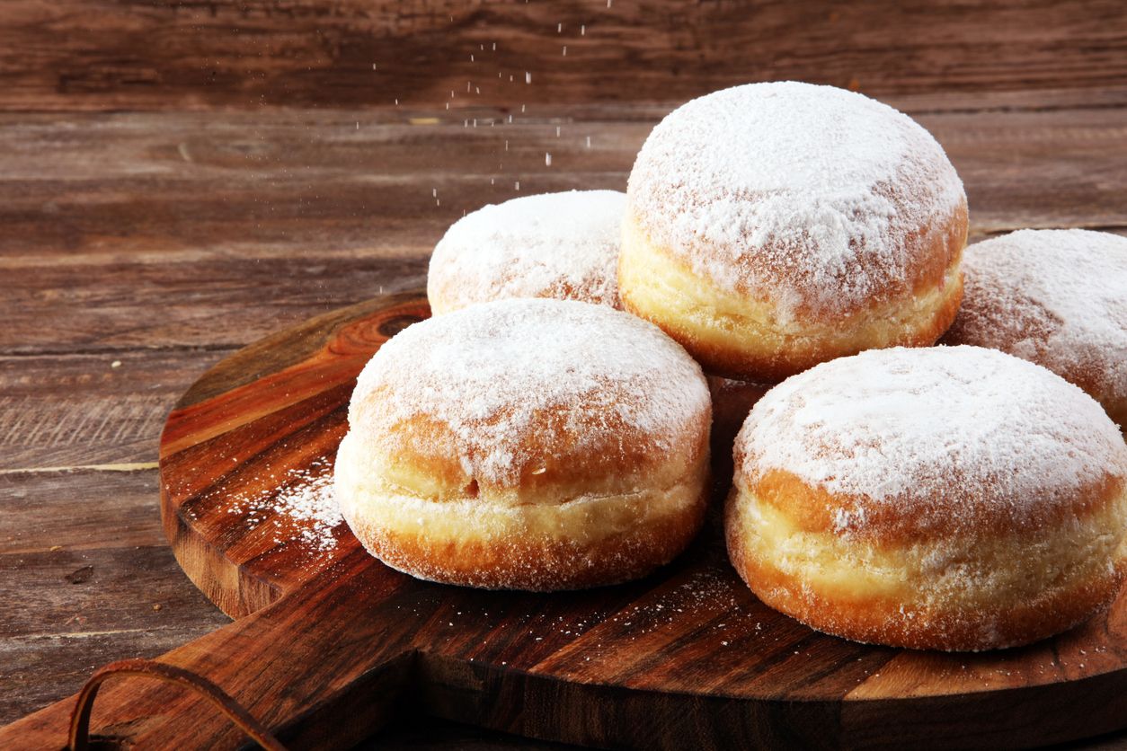 German donuts with jam and icing sugar. Carnival powdered sugar raised donuts.