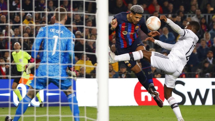 Barcelonas Ronald Araujo, center, heads the ball past Manchester Uniteds Tyrell Malacia during the Europa League playoff first leg soccer match between Barcelona and Manchester United at the Camp Nou stadium in Barcelona, Spain, Thursday, Feb. 16, 2023. (AP Photo/Joan Monfort)
