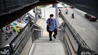 Seorang calon penumpang menaiki JPO menuju Halte TransJakarta Cikoko Stasiun Cawang.