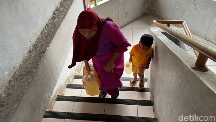 Muryati (46) dan putranya yang masih kecil mengangkut air dari lantai dasar sampai lantai 5 Rusun Marunda. 17 Februari 2023. (Devi Puspitasari/detikcom)