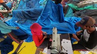 Mereka menggunakan mesin jahit dalam proses perbaikan jaring.
