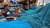 Para nelayan membetulkan jaring yang rusak saat bersandar di Pelabuhan Muara Angke, Jakarta Utara, Jumat (17/2/2023).