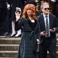 Christina Hendricks mengenakan coat dress motif kotak-kotak dengan lapel beludru hitam. Bros bentuk pita menjadi pelengkap gayanya. Foto: WireImage/Karwai Tang