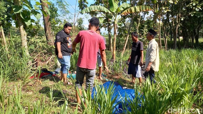 Polisi dibantu warga menggali sejumlah barang milik almarhum suami instruktur senam yang dikubur di belakang rumah