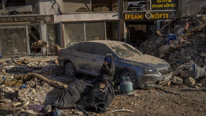 Kondisi Terkini Antakya, Kota Paling Terdampak Gempa Turki-Suriah A woman sits next to bodies that were pulled from the rubble of a destroyed building in Antakya, southeastern Turkey, Wednesday, Feb. 15, 2023. The earthquakes that killed more than 39,000 people in southern Turkey and northern Syria is producing more grieving and suffering along with extraordinary rescues and appeals for aid. (AP Photo/Bernat Armangue)