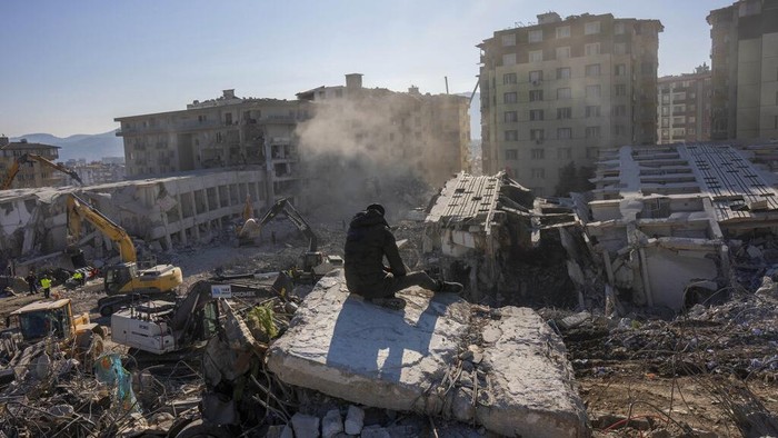 A man sits atop the rubble of collapsed buildings during the earthquake in Antakya, southeastern Turkey, Tuesday, Feb. 14, 2023. The death toll from the earthquakes of Feb. 6, that struck Turkey and northern Syria is still climbing. (AP Photo/Bernat Armangue)
