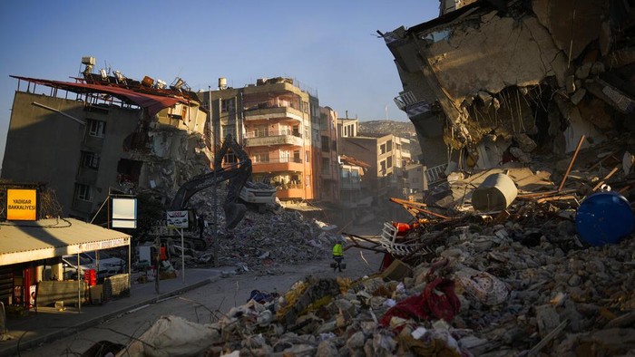 A man carries buckets as he walks among destroyed buildings after the earthquake in Samandag, southern Turkey, Thursday, Feb. 16, 2023. The number of people killed in the Feb. 6 earthquakes that devastated parts of southern Turkey and northern Syria continues to rise. As chances of finding more survivors dwindled, some foreign search teams that rushed in to help have started leaving. (AP Photo/Francisco Seco)