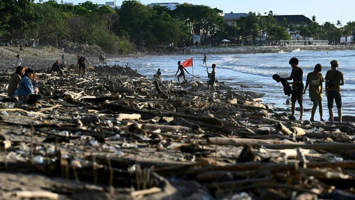 Penampakan Pantai Kuta yang Dibanjiri Sampah Kayu A tourist walks between debris and rubbish washed ashore at Kuta Beach, on Indonesia's resort island of Bali on February 18, 2023. (Photo by SONNY TUMBELAKA / AFP) (Photo by SONNY TUMBELAKA/AFP via Getty Images)