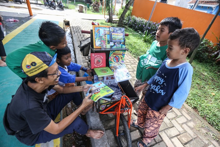 Pemilik kargo baca Edi Dimyati (kiri) berbincang dengan anak-anak yang ingin membaca buku di kargo baca di RPTRA Cibubur Berseri, Jakarta Timur, Minggu (19/2/2023). Kargo Baca merupakan perpustakaan keliling menggunakan sepeda yang dibuat oleh Edi Dimyati guna mempermudah akses membaca untuk anak serta meningkatkan minat baca. ANTARA FOTO/Asprilla Dwi Adha/aww.