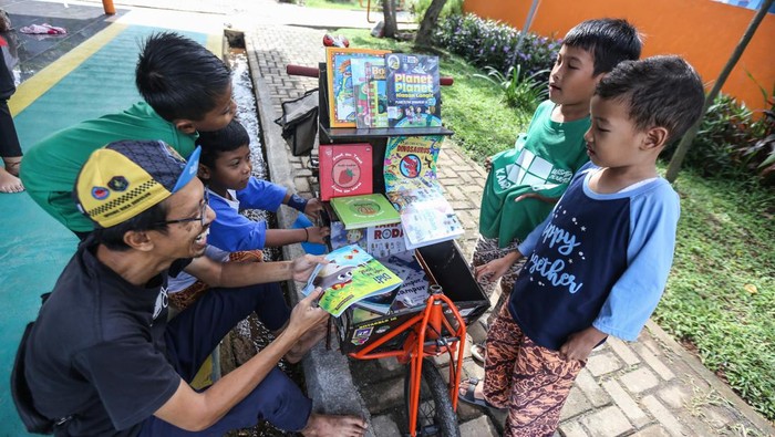 Pemilik kargo baca Edi Dimyati (kiri) berbincang dengan anak-anak yang ingin membaca buku di kargo baca di RPTRA Cibubur Berseri, Jakarta Timur, Minggu (19/2/2023). Kargo Baca merupakan perpustakaan keliling menggunakan sepeda yang dibuat oleh Edi Dimyati guna mempermudah akses membaca untuk anak serta meningkatkan minat baca. ANTARA FOTO/Asprilla Dwi Adha/aww.
