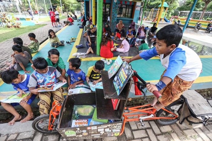 Pemilik kargo baca Edi Dimyati (kiri) berbincang dengan anak-anak yang ingin membaca buku di kargo baca di RPTRA Cibubur Berseri, Jakarta Timur, Minggu (19/2/2023). Kargo Baca merupakan perpustakaan keliling menggunakan sepeda yang dibuat oleh Edi Dimyati guna mempermudah akses membaca untuk anak serta meningkatkan minat baca. ANTARA FOTO/Asprilla Dwi Adha/aww.