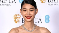 Hoyeon mengenakan gaun keemasan yang berkilau saat terkena sorot cahaya. Dia melengkapi penampilannya dengan aksesori kalung dan cincin silver. (Foto: Gareth Cattermole/Getty Images f/Gareth Cattermole/BAFTA) 
