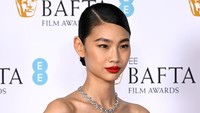 Alis tebal, lipstik merah menyala, dan tatanan rambut klimis jadi gaya Hoyeon. (Foto: Gareth Cattermole/Getty Images f/Gareth Cattermole/BAFTA) 