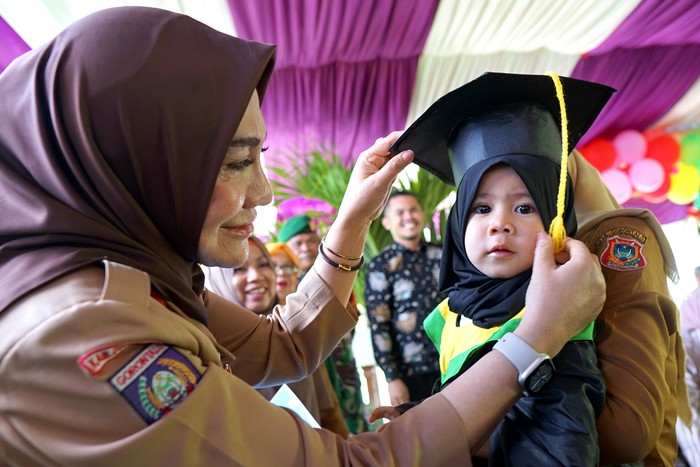 Ketua Tim Penggerak PKK Kabupaten Gorontalo Fory Naway (kiri) mewisuda balita lengkap imunisasi di Desa Dulomo, Kabupaten Gorontalo, Gorontalo, Senin (20/2/2023). Wisuda balita merupakan program Pemerintah Kabupaten Gorontalo untuk meningkatkan jumlah kepesertaan bayi yang diimuniasi sebagai upaya pencegahan tengkes (stunting) serta menjadi salah satu syarat untuk masuk Pendidikan Anak Usia Dini (PAUD). ANTARA FOTO/Adiwinata Solihin/rwa.