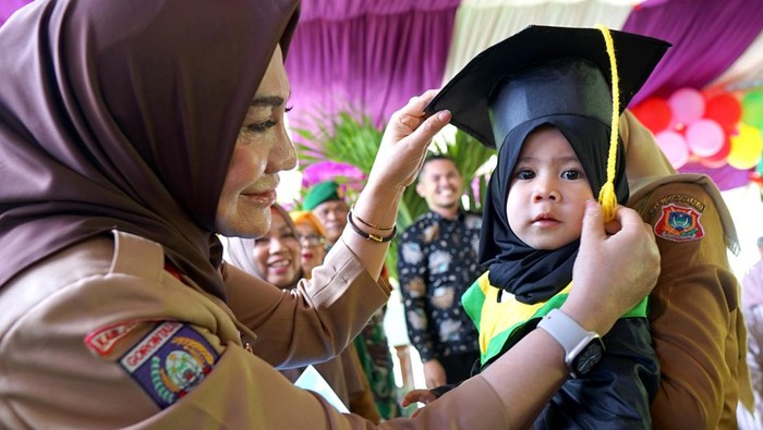 Gemasnya Balita di Gorontalo Pakai Toga Saat Wisuda Imunisasi Ketua Tim Penggerak PKK Kabupaten Gorontalo Fory Naway (kiri) mewisuda balita lengkap imunisasi di Desa Dulomo, Kabupaten Gorontalo, Gorontalo, Senin (20/2/2023). Wisuda balita merupakan program Pemerintah Kabupaten Gorontalo untuk meningkatkan jumlah kepesertaan bayi yang diimuniasi sebagai upaya pencegahan tengkes (stunting) serta menjadi salah satu syarat untuk masuk Pendidikan Anak Usia Dini (PAUD). ANTARA FOTO/Adiwinata Solihin/rwa.