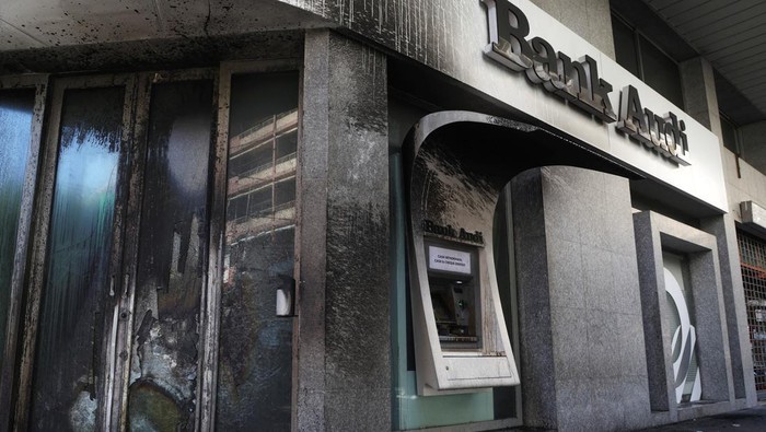 A demonstrator gestures near a bank, set on fire, during a protest organized by Depositors' Outcry, a group campaigning for angry depositors, against informal restrictions on cash withdrawals and deteriorating economic conditions in Beirut, Lebanon February 16, 2023. (REUTERS/Mohamed Azakir)
