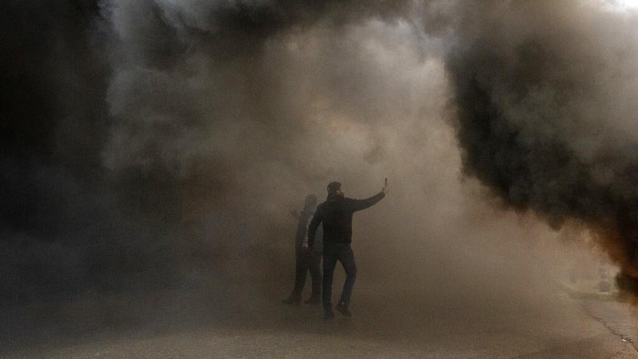 Krisis Lebanon Bikin Miris! Banyak Bank Dibakar Nasabah A protester holds Lebanese pounds as he stands in front of burning tires they set on fire, in front the Central Bank building, where the anti-government demonstrators rally against the Lebanese Central Bank Governor Riad Salameh and the deepening financial crisis in Beirut, Lebanon, Wednesday, Jan. 25, 2023. (AP Photo/Hassan Ammar)