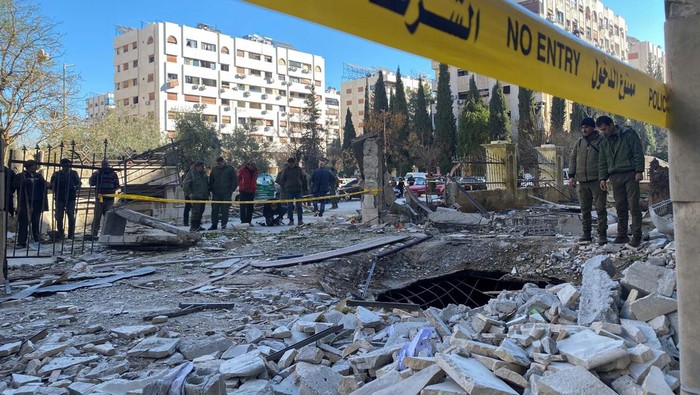 Police officers stand on the rubble of a damaged building at the site of a rocket attack, in central Damascus Kafr Sousa neighborhood, Syria, February 19, 2023. REUTERS/Firas Makdesi