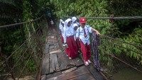 Sejumlah siswa Sekolah Dasar berjalan di jembatan gantung yang rusak di Desa Sudamanik, Lebak, Banten, Senin (20/2/2023).