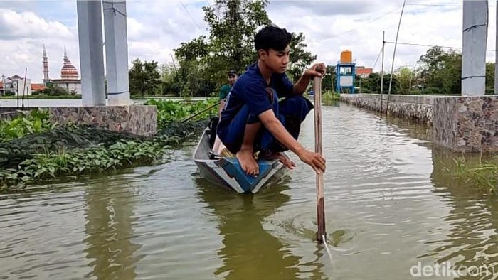 Warga menggunakan perahu di tengah banjir luapan Bengawan Njero