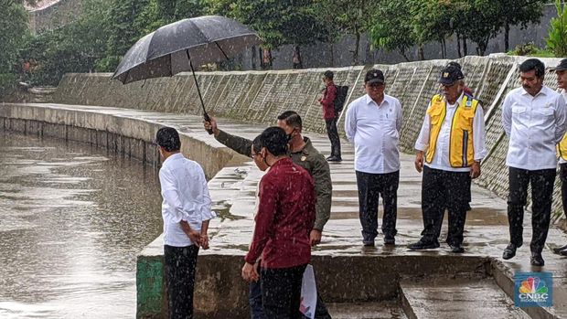 Di tengah hujan lebat Presiden Joko Widodo melakukan peninjauan titik normalisasi kali Ciliwung, yang berada di Jalan Inspeksi Ciliwung, Jakarta Selatan, pada Selasa (21/2/2023). (CNBC Indonesia/Emir Yanwardhana)