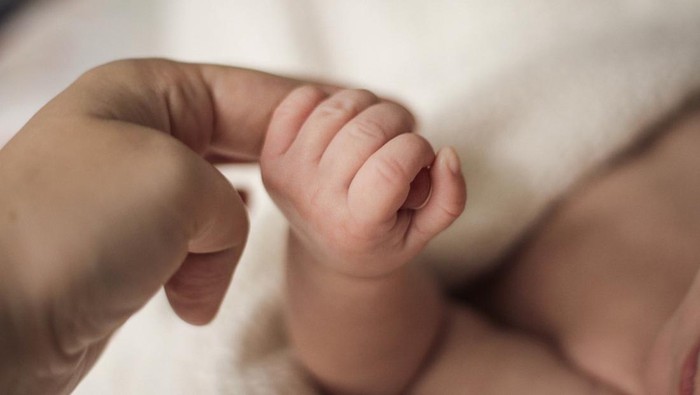 child hand squeezes adult finger, holding mothers hand.  The concept of empathy, trust, care and tenderness of motherhood. blurred background