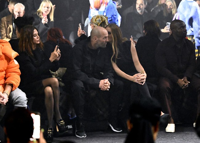 Duduk di front row, sejoli yang tampil kompak dalam balutan busana serba hitam ini sesekali menunjukkan kemesraan. (Foto: Gareth Cattermole/BFC/Getty Images)