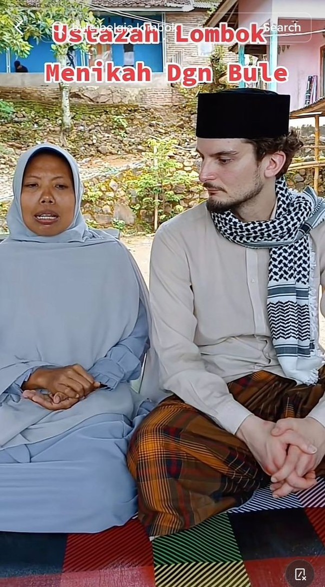 Jawad tampak mengenakan peci hitam, sorban yang dililitkan ke leher, baju koko, dan sarung. Sedangkan sang ustazah memakan hijab dan gamis warna royal blue. Foto: Dok. TikTok @lombokdokumen.