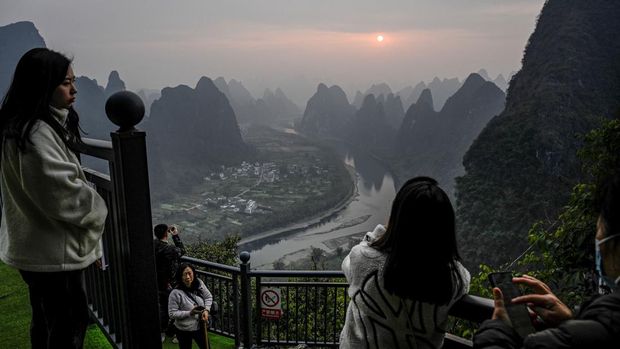 Tourists watch the sunrise at a scenic tourist spot on Xianggong Mountain, on the west bank of Li River in Yangshuo city, in southern China's Guangxi province on February 21, 2023. (Photo by Jade Gao / AFP) (Photo by JADE GAO/AFP via Getty Images)